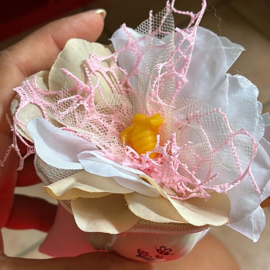 Vasetto di ceramica bianca con fascia di juta e un grande fiore di stoffa