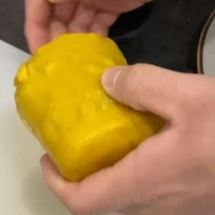 Le mani che modellano la cera d'api attorno alla carne