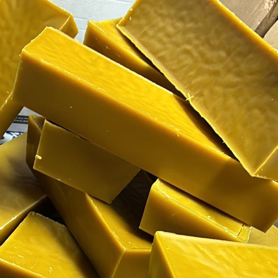 Un cartone pieno di panetti di cera d'api pura, gialli e lucidi