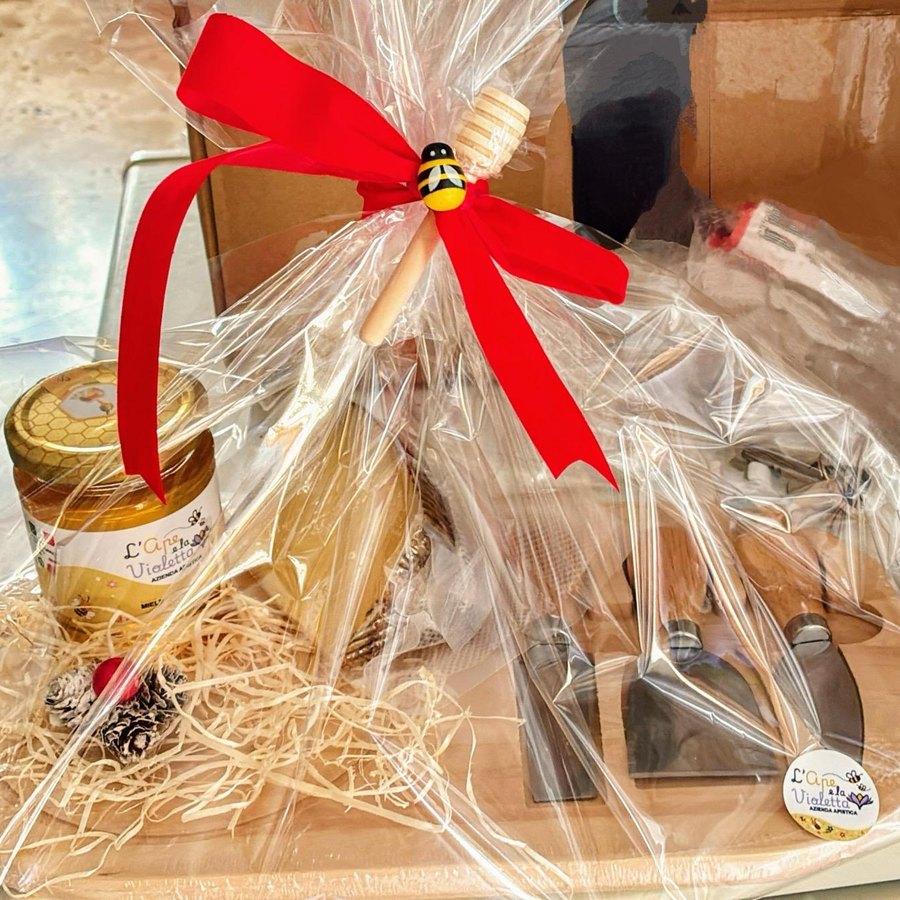 Cesto regalo su tagliere di legno chiuso in cellophane con un grande fiocco rosso