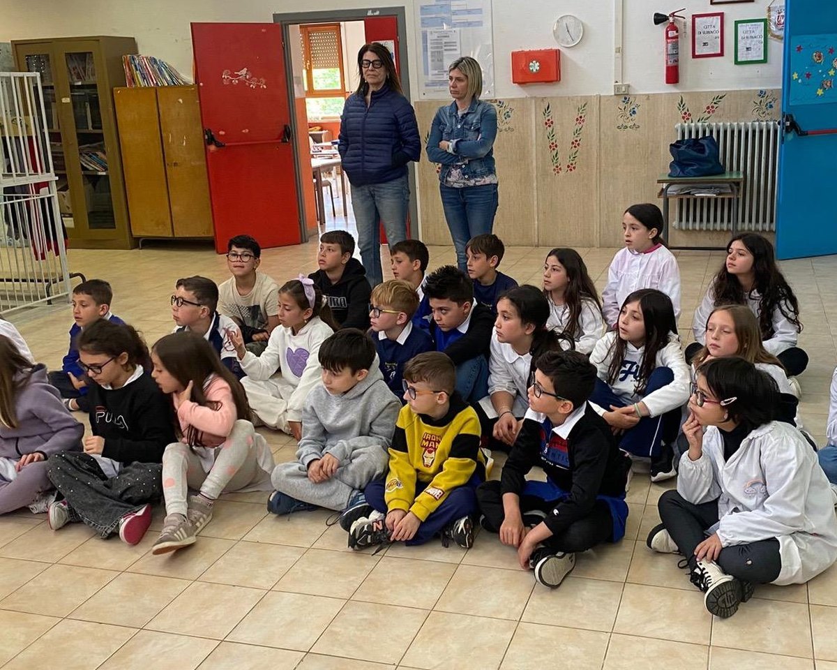 I bambini seduti a semicerchio durante l'incontro con l'apicoltrice